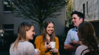 Menschen unterhalten sich bei Kaffee im freien und lachen