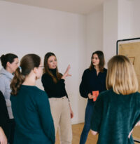 Eine Beraterin spricht mit Teilnehmer:innen einer Teamentwicklungsgruppe