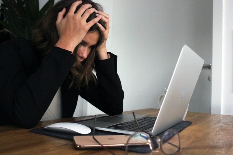 Eine Frau sitzt gestresst vor ihrem Laptop