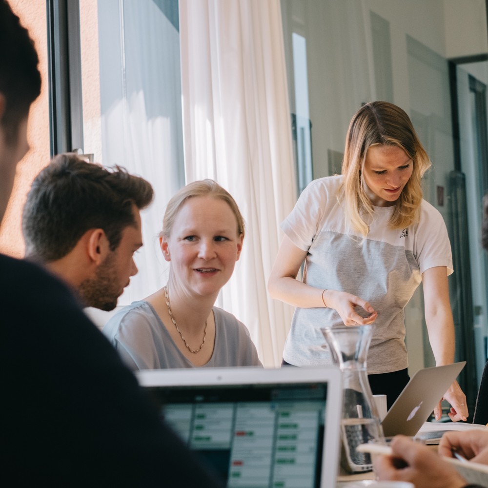 Ein Team diskutiert Lösungen an einem Tisch im IOS Institut.