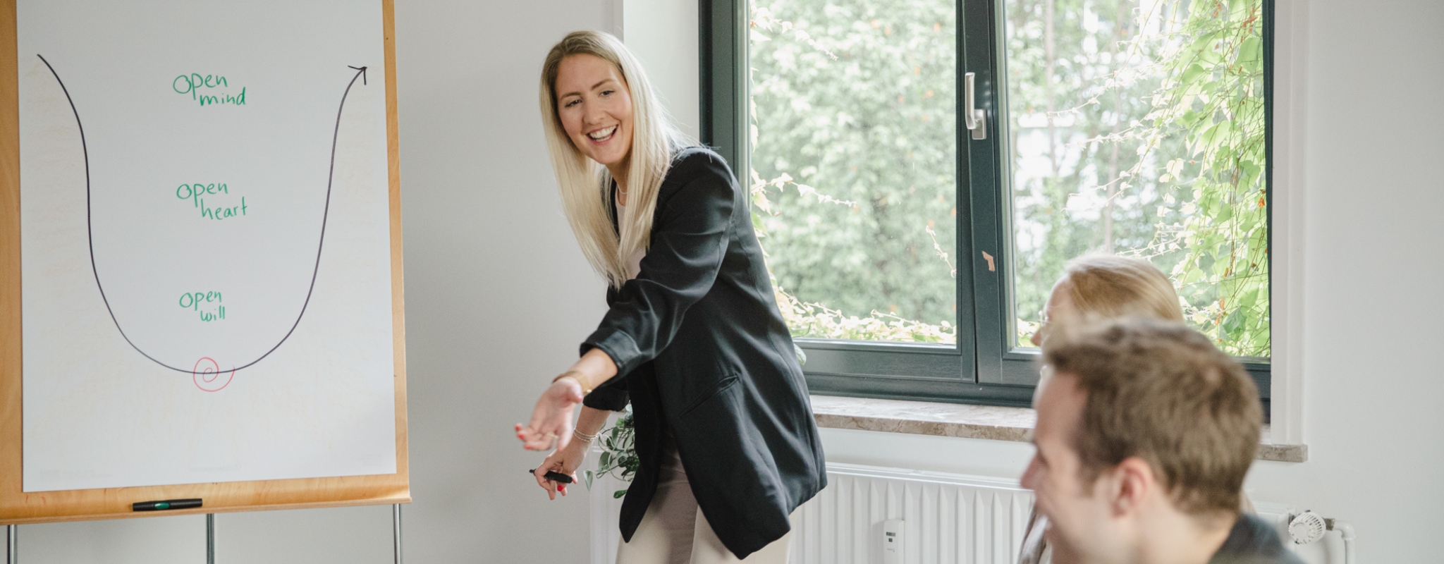 IOS Beraterin Lara Hahn erklärt Teilnehmer:in einer Ausbildung ein systemisches Modell