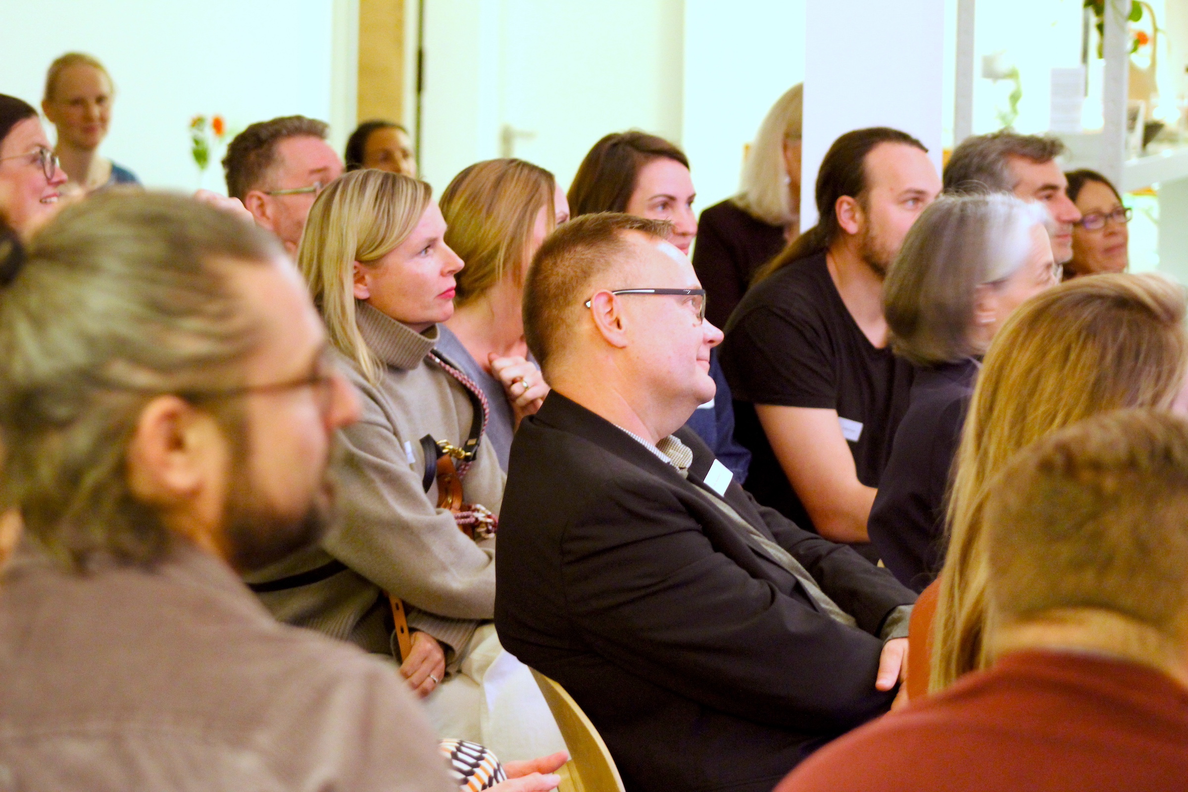 Teilnehmer:innen schauen beim Netzwerkabend der IOS Akademie gespannt auf die Bühne.